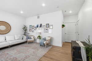 Living area with light wood-type flooring and recessed lighting
