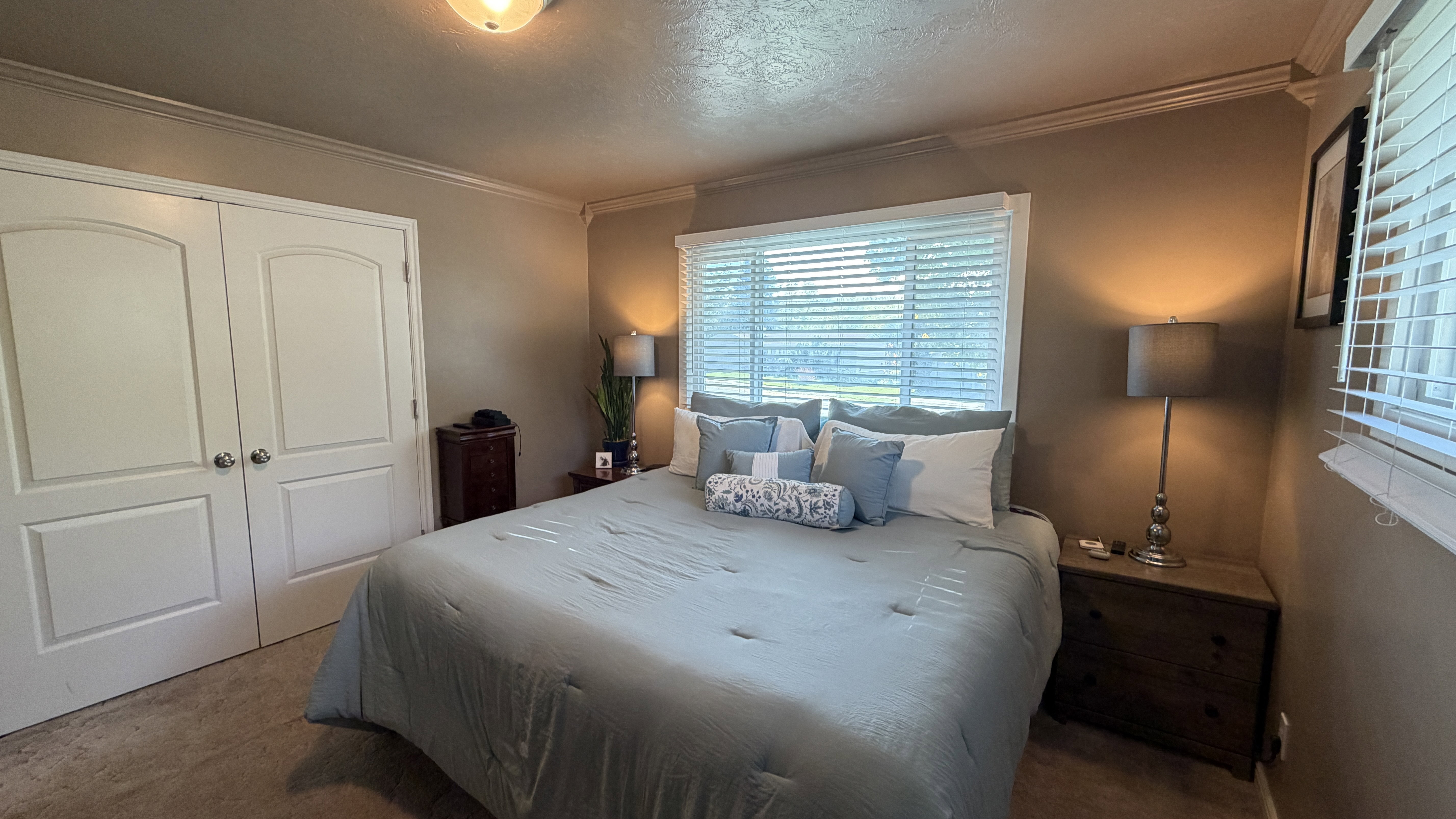 Bedroom 1 with a textured ceiling, carpet flooring, ornamental molding, and a larger closet