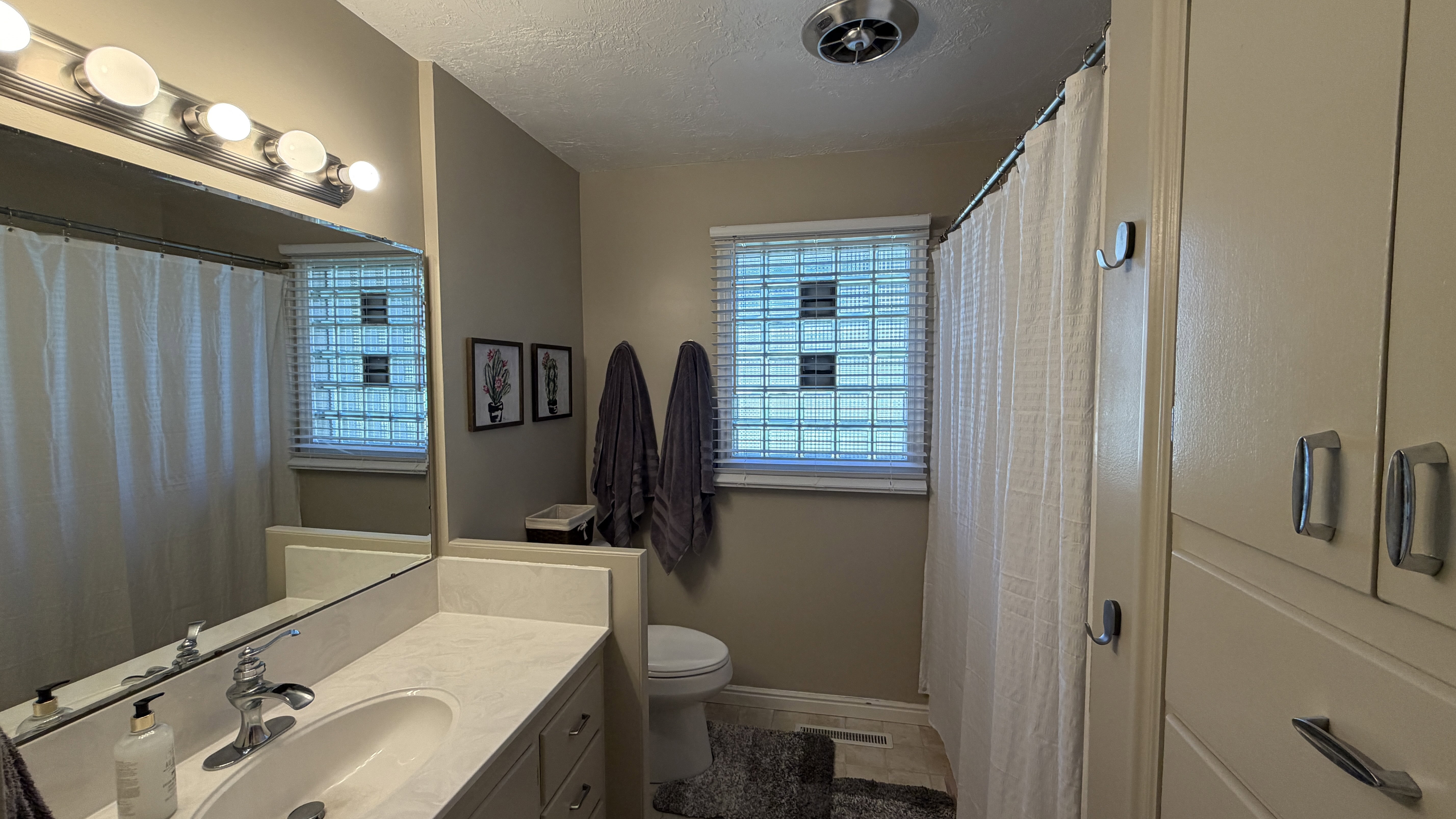Bathroom featuring vanity, a textured ceiling, and curtained shower, linen closet and built in drawers