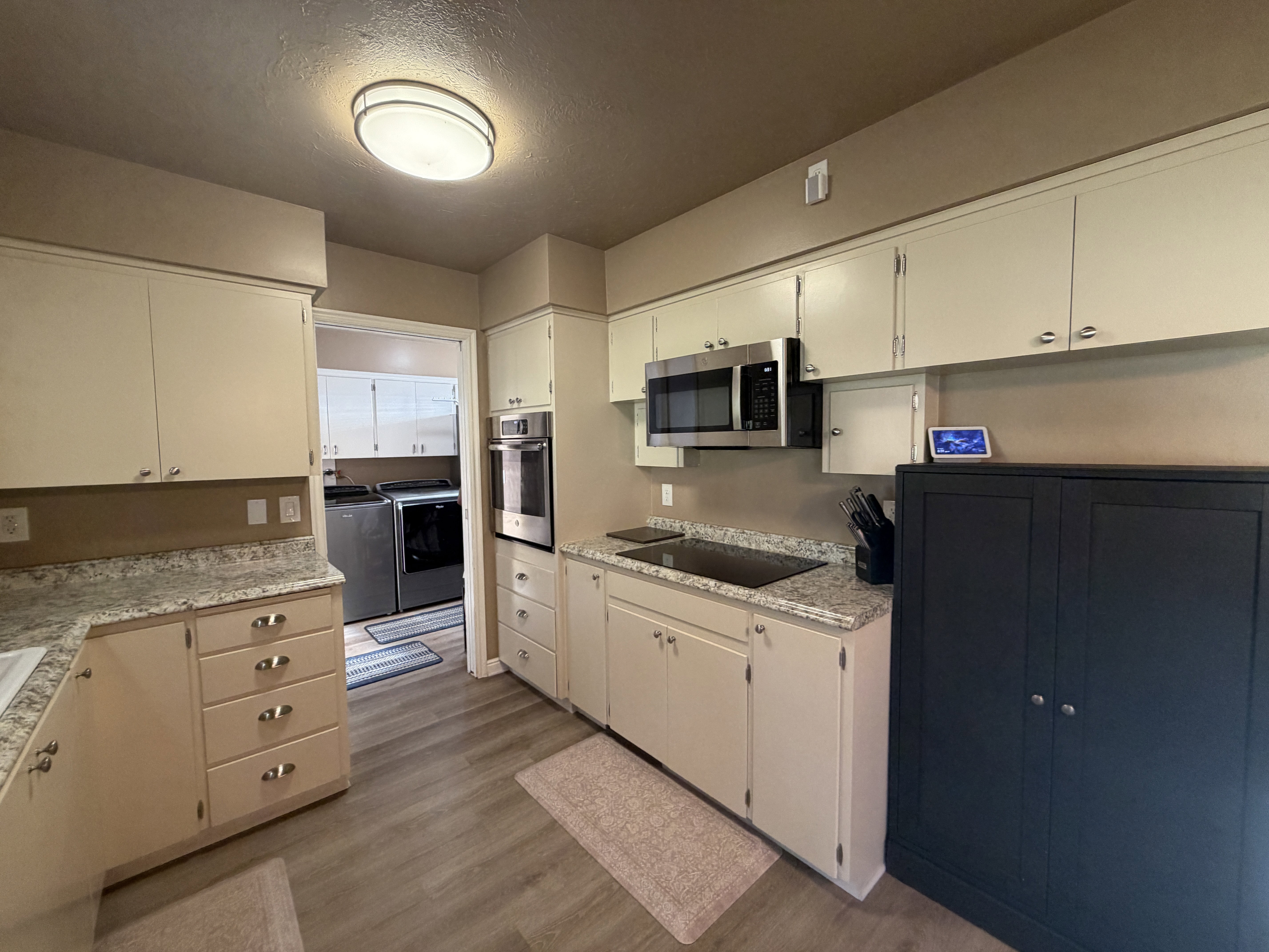 Kitchen with separate washer and dryer, stainless steel appliances, light wood finished floors, a textured ceiling, and cream cabinets