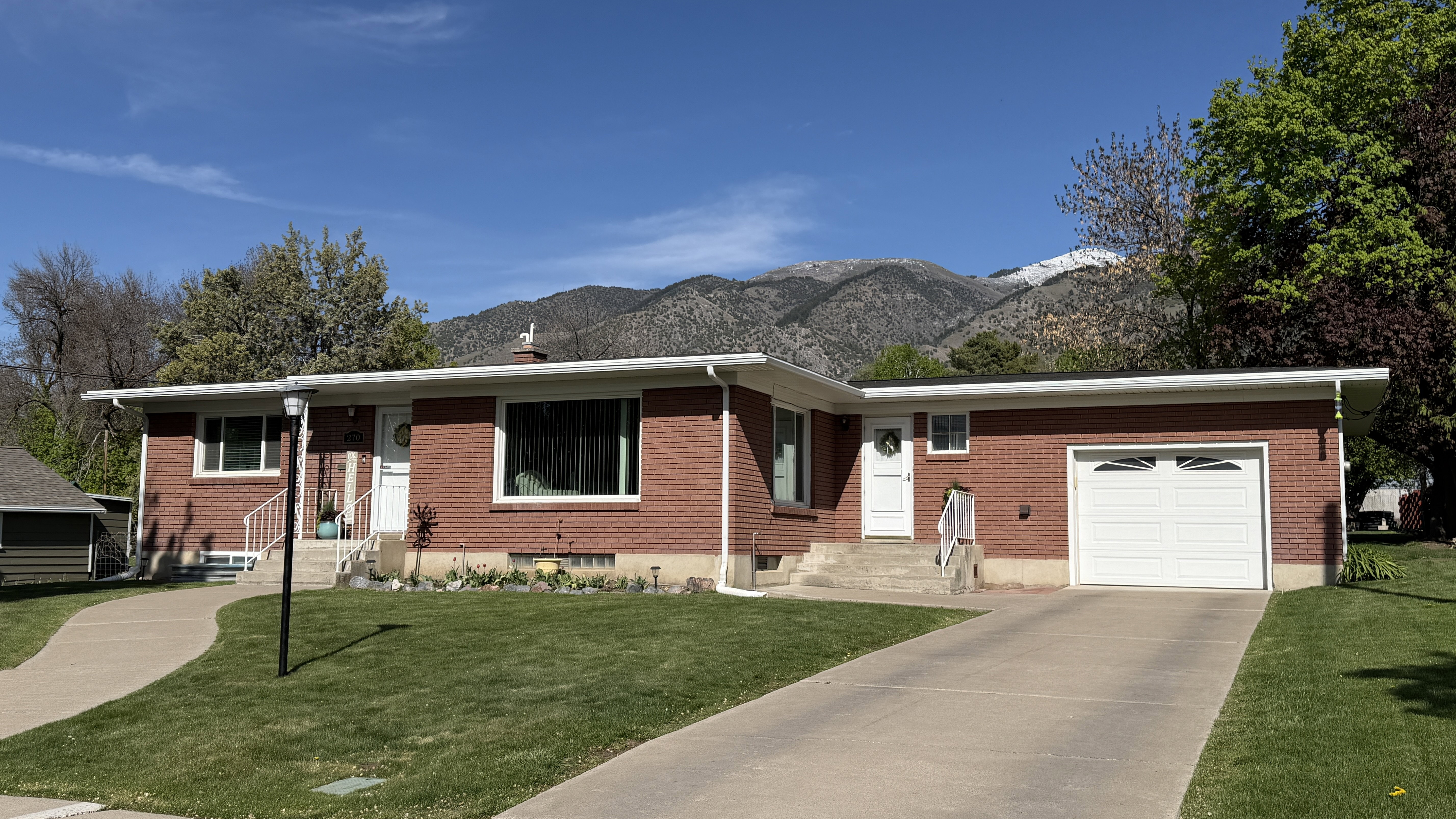 Single story home featuring brick siding, concrete driveway, a garage, and a front yard