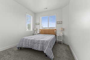 Bedroom featuring baseboards and dark carpet