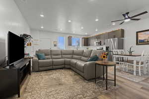 Living room featuring light wood-style flooring, a ceiling fan, and recessed lighting