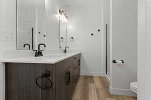 Full bath featuring double vanity, light wood-style flooring, and a shower stall