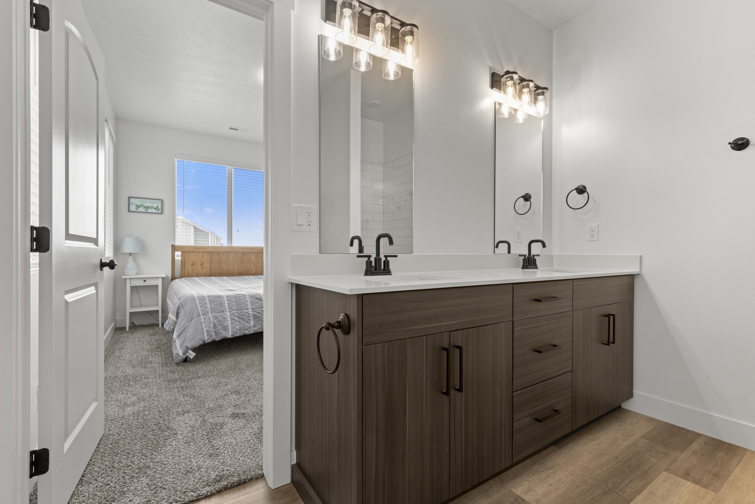 Ensuite bathroom with double vanity and light wood-style flooring