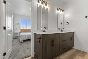 Ensuite bathroom with double vanity and light wood-style flooring