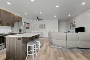 Living room featuring light wood-type flooring, ceiling fan, and recessed lighting