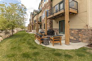 View of green lawn featuring a patio, an outdoor fire pit, and a balcony