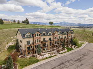 View of front facade with stone siding, a mountain view, and a front yard