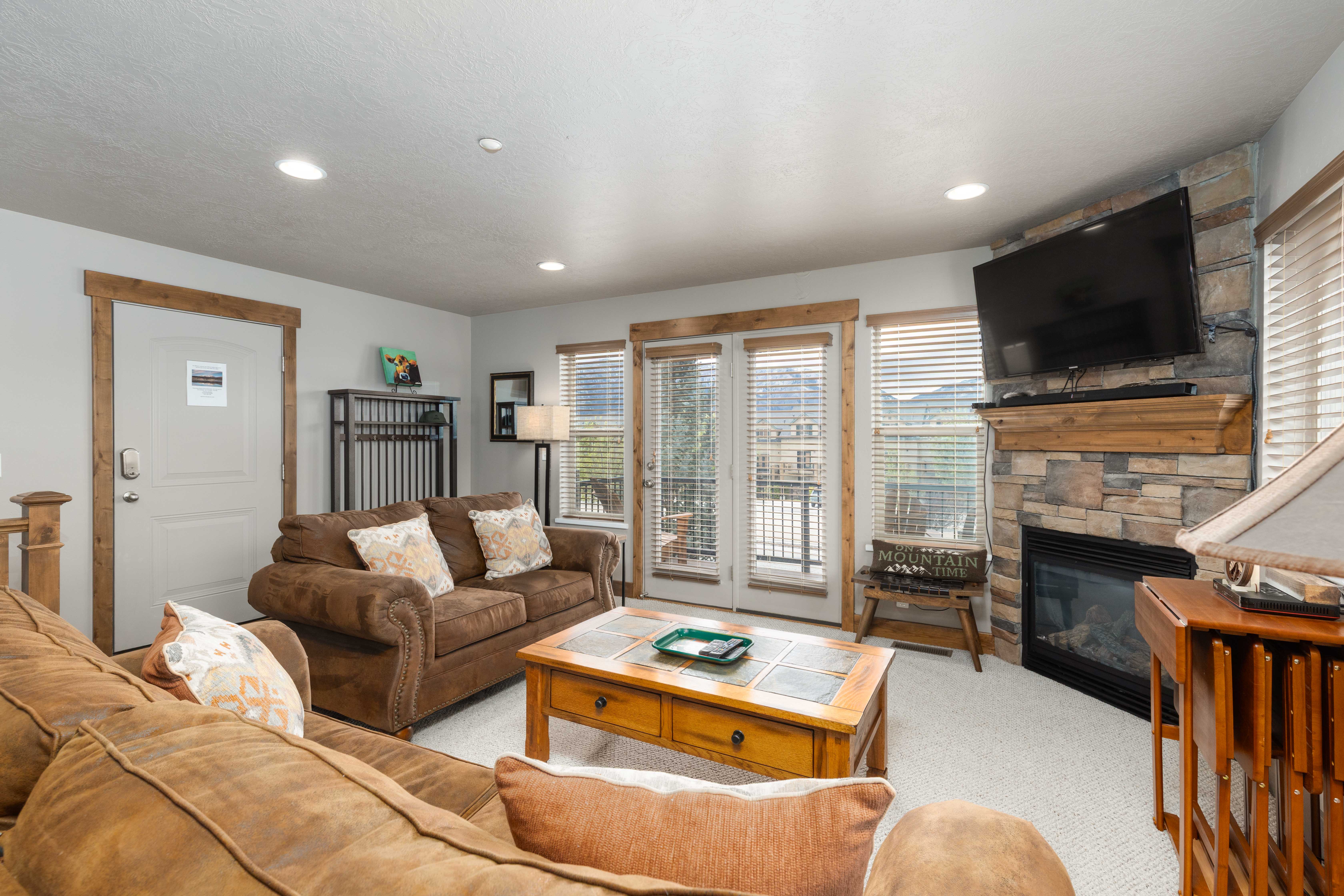 Carpeted living room featuring a stone fireplace and recessed lighting