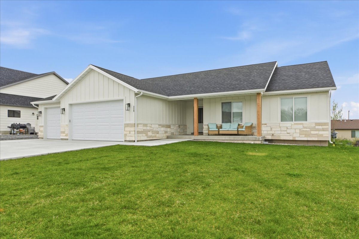 Ranch-style house with board and batten siding, stone siding, covered porch, and a garage