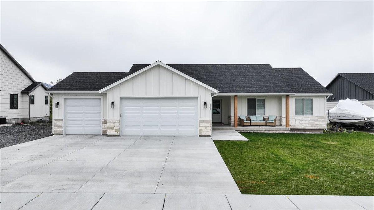 Ranch-style home featuring a porch, a garage, board and batten siding, a shingled roof, and a front yard