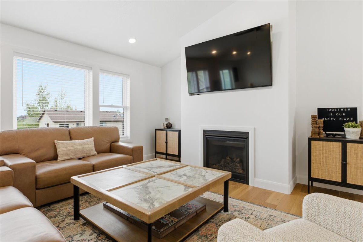 Living area with wood finished floors, vaulted ceiling, a glass covered fireplace, and recessed lighting