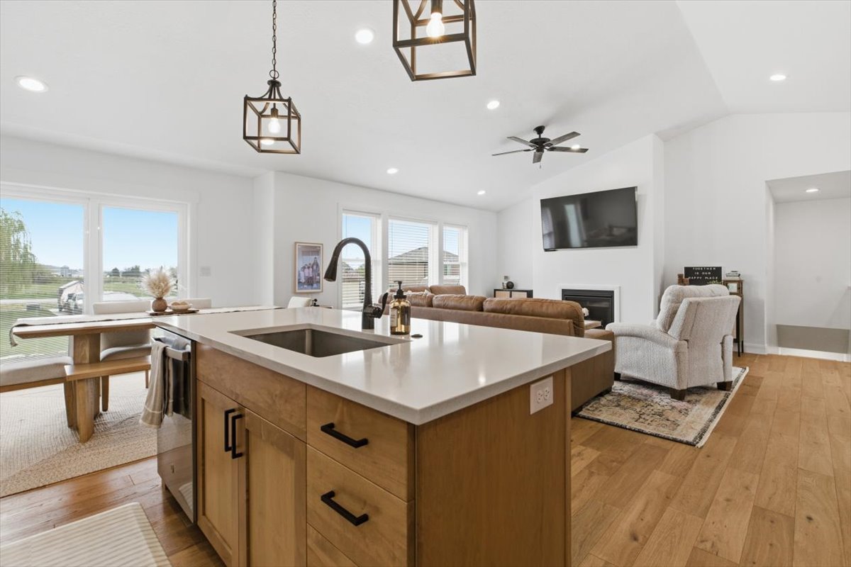 Kitchen with open floor plan, hanging light fixtures, light wood finished floors, an island with sink, and lofted ceiling