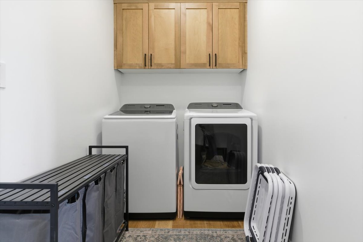 Laundry room with separate washer and dryer, cabinet space, and wood finished floors