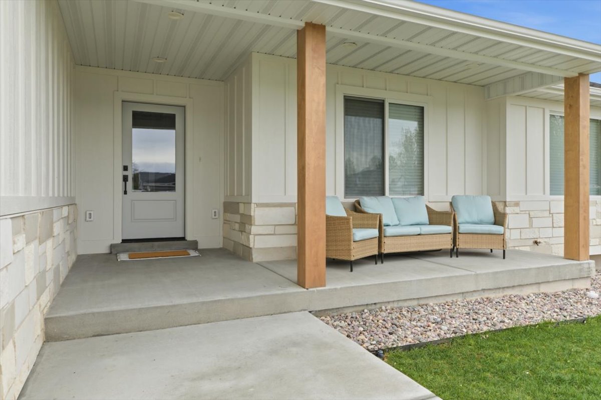 View of exterior entry featuring board and batten siding, covered porch, and stone siding
