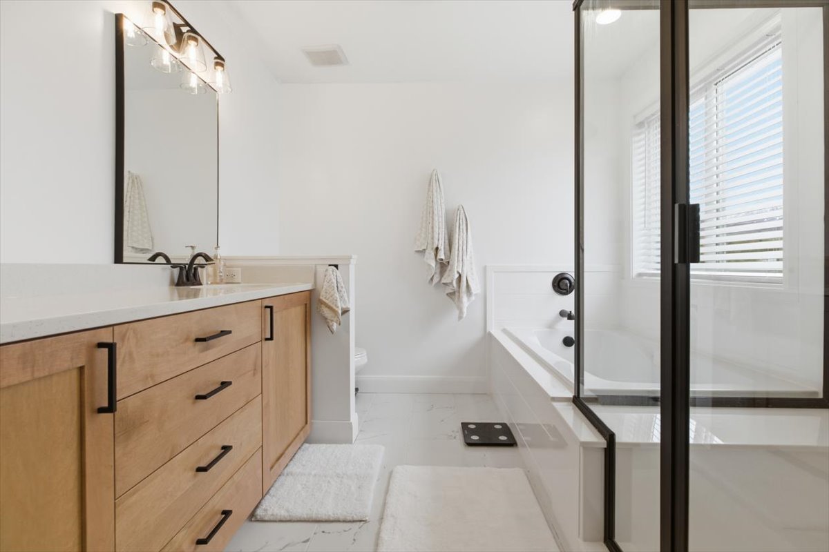 Bathroom with vanity, a bath, and a stall shower
