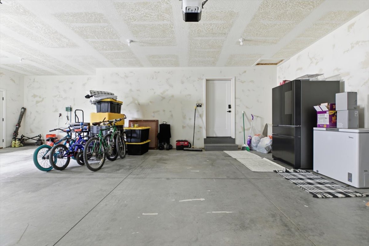 Garage with freestanding refrigerator, white fridge, and a garage door opener