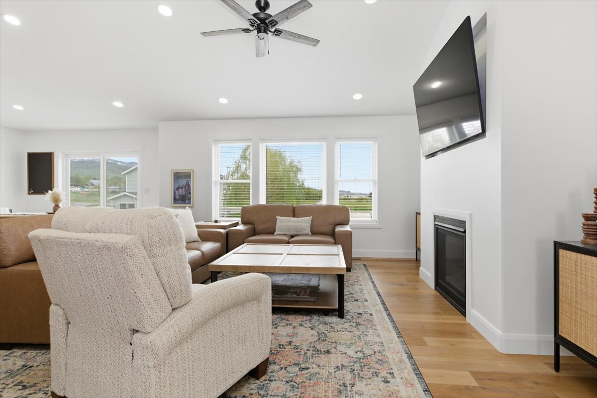 Living area featuring ceiling fan, light wood-style floors, a glass covered fireplace, and recessed lighting