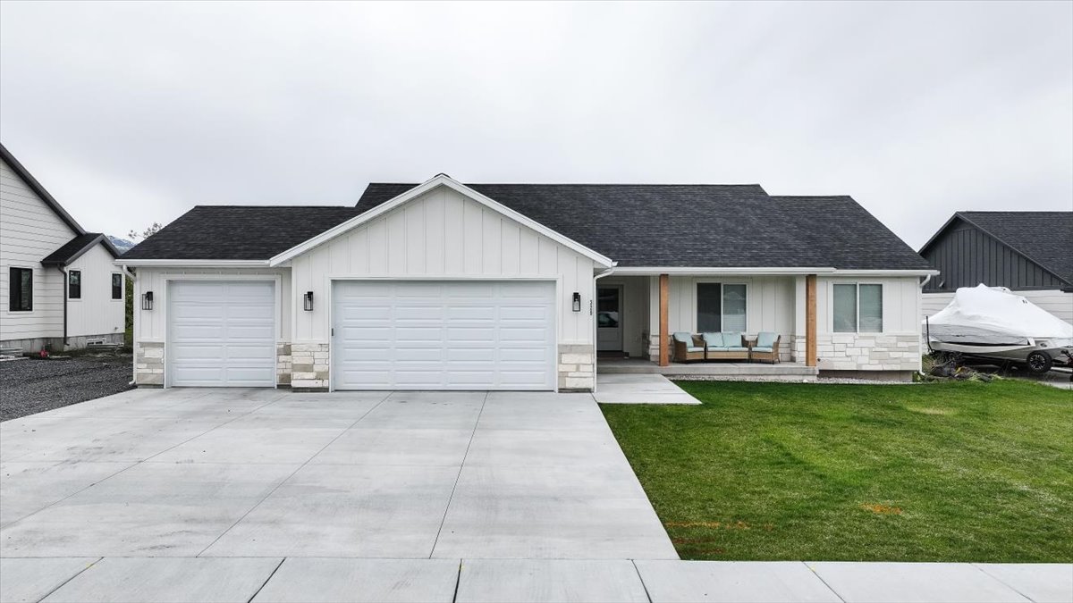 Single story home with covered porch, an attached garage, board and batten siding, stone siding, and a shingled roof