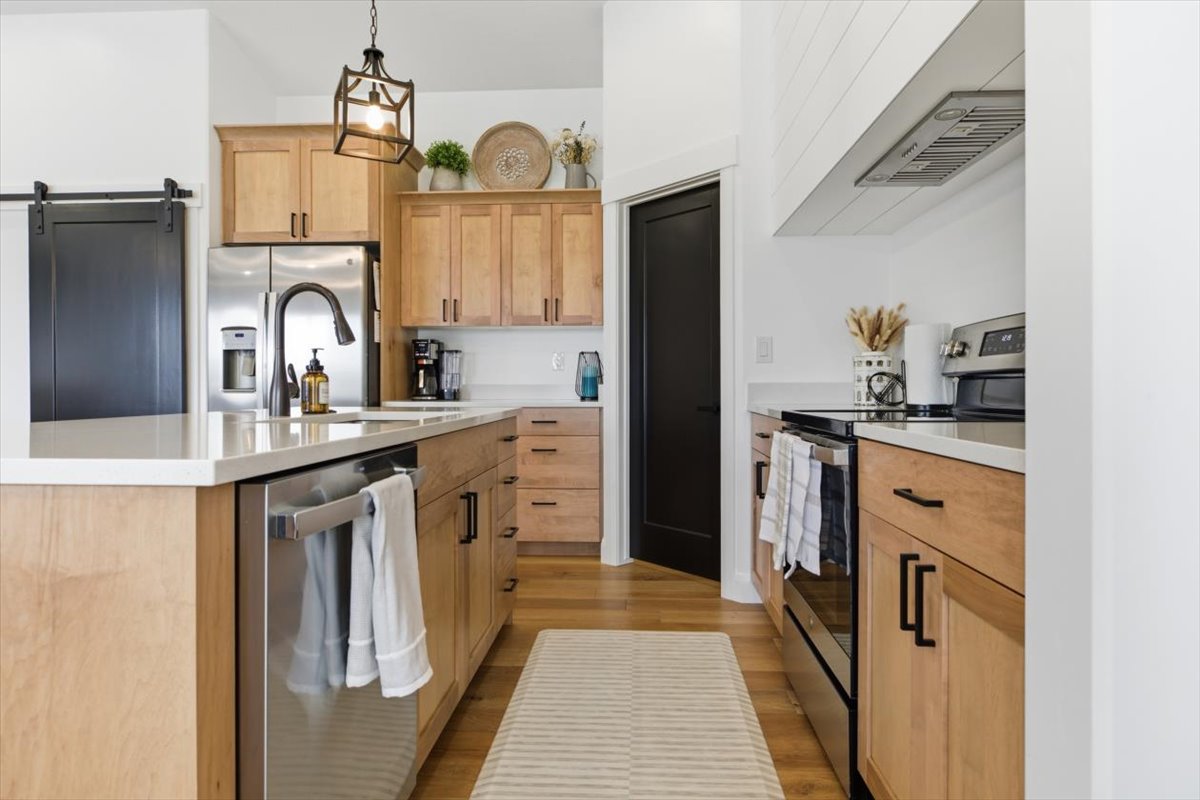 Kitchen with stainless steel appliances, a barn door, light wood-style floors, and light wood finish cabinets