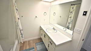 Full bathroom with vanity, dark wood-style flooring, and shower / tub combo with curtain