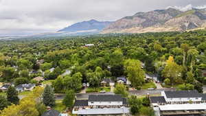 Aerial view of residential area featuring a mountainous background and a heavily wooded area