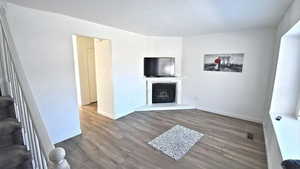Unfurnished living room featuring dark wood finished floors and a fireplace with raised hearth
