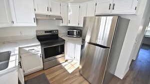Kitchen with stainless steel appliances, light stone countertops, and white cabinets