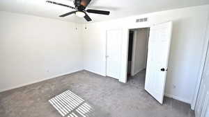 Unfurnished bedroom featuring dark carpet and ceiling fan