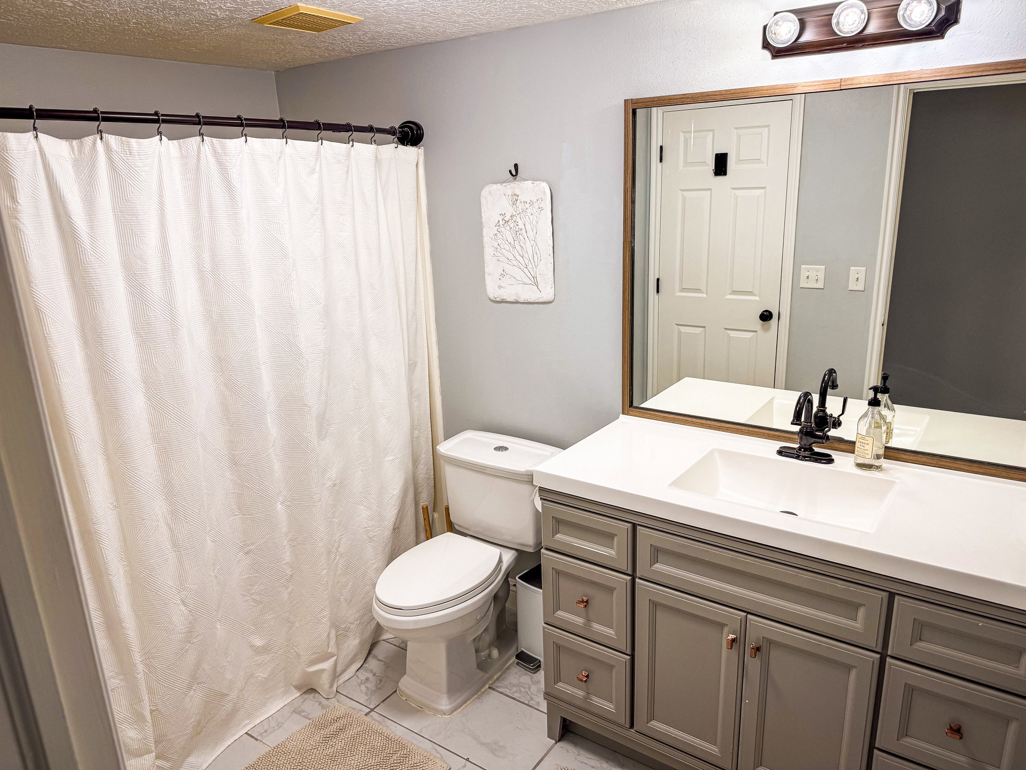 Full bath with vanity, a shower with shower curtain, a textured ceiling, and light marble finish flooring
