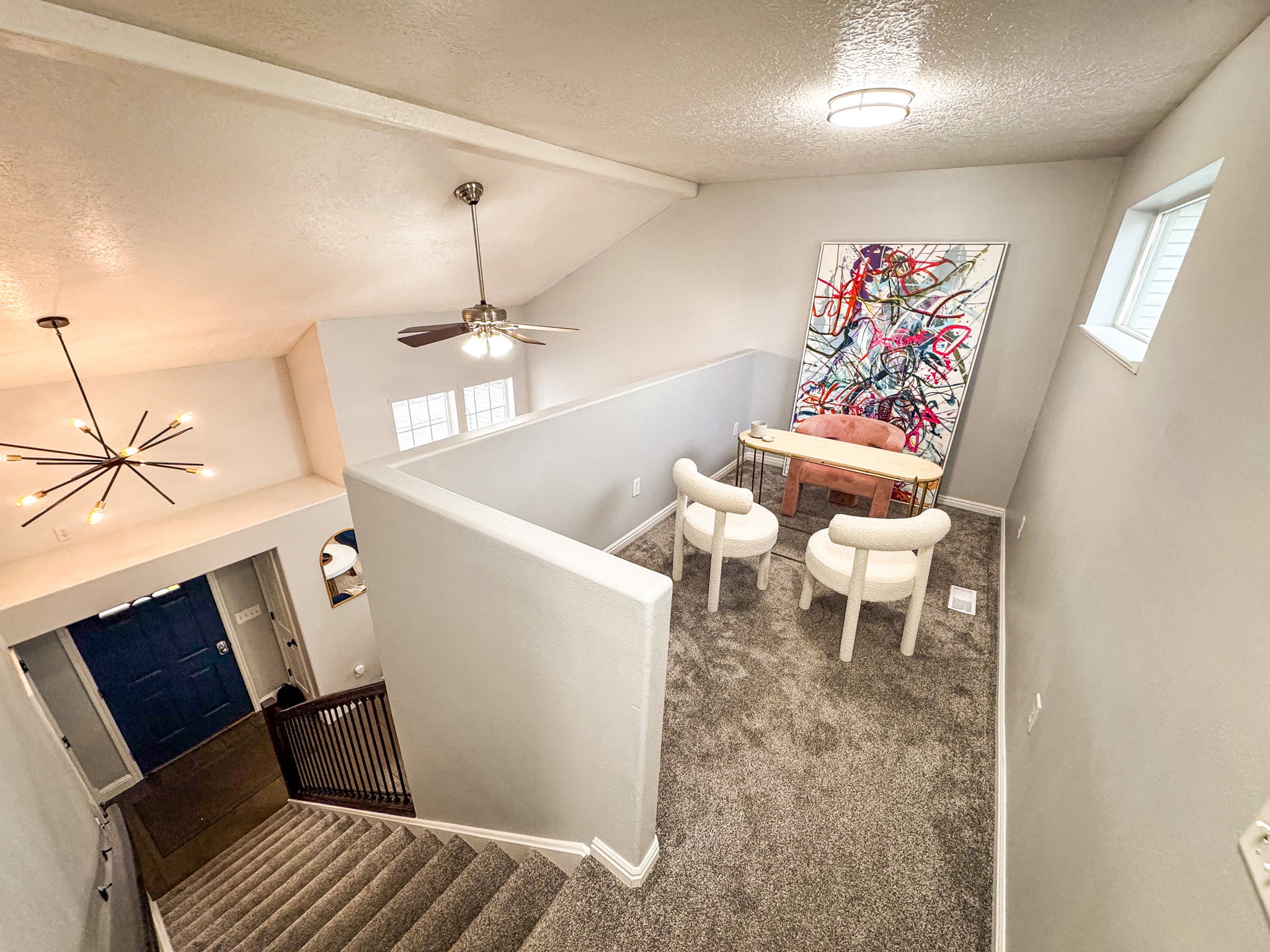 Staircase featuring a textured ceiling, beam ceiling, carpet floors, ceiling fan, and a chandelier