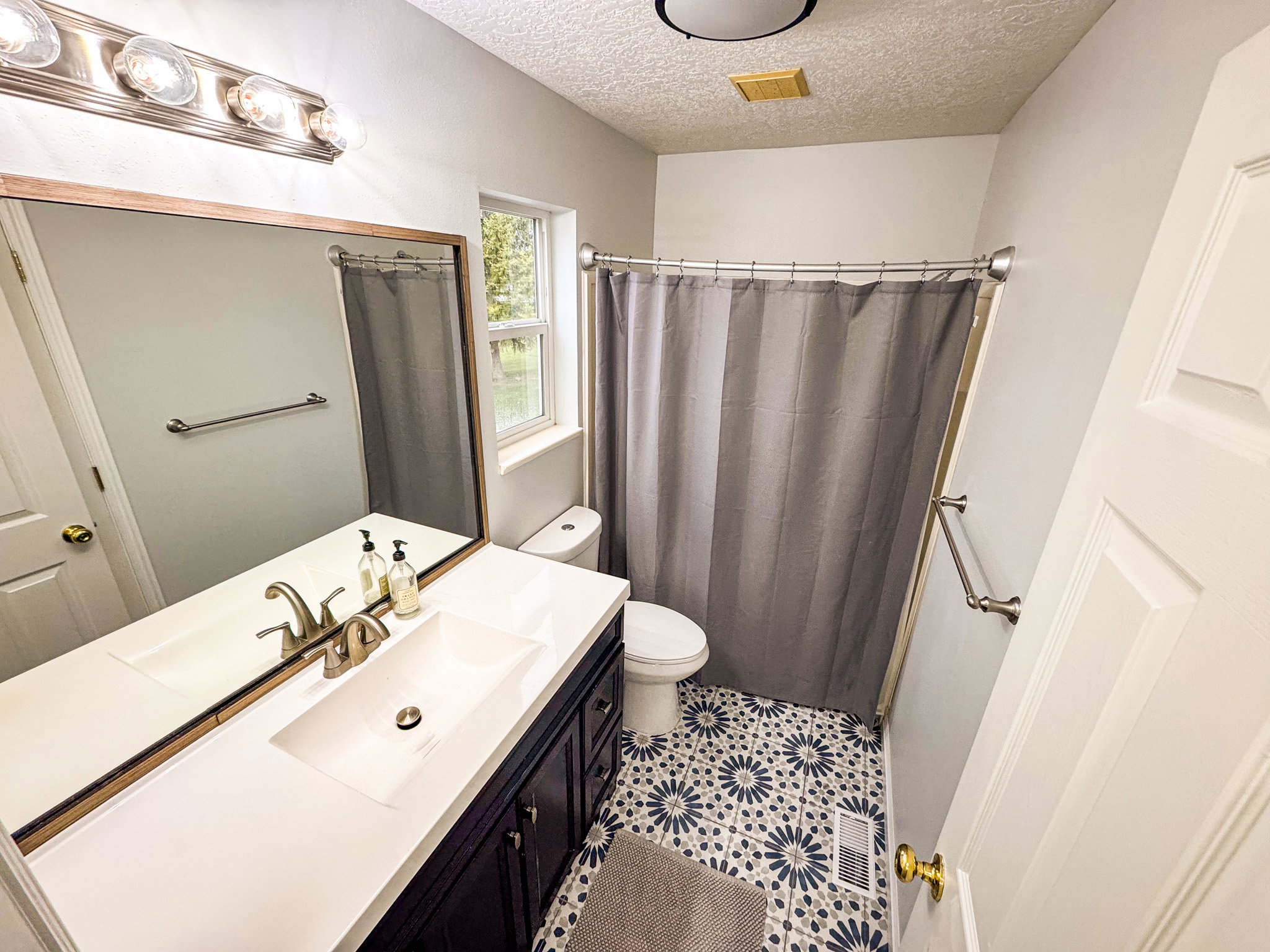 Full bathroom featuring vanity, curtained shower, a textured ceiling, and light tile patterned flooring