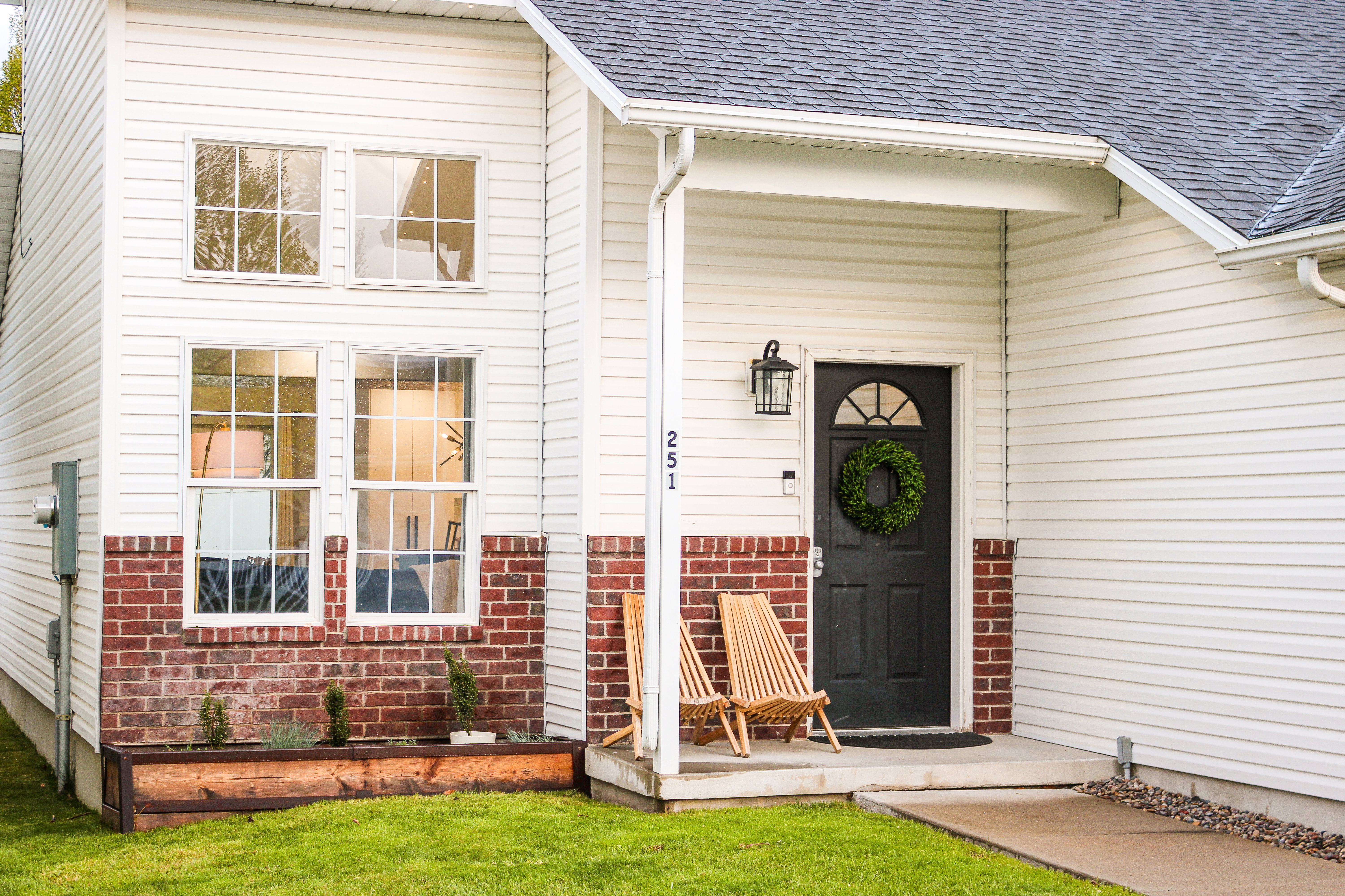 Entrance to property featuring roof with shingles, brick siding, and a lawn