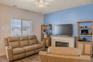 Living area featuring a mounted ceiling fan, wood-finish flooring, and a window with blinds