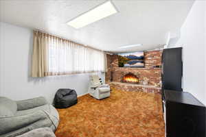 Carpeted basement living room with a brick fireplace