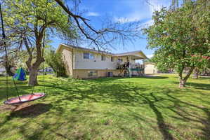 Rear view of property featuring brick siding and a large landscaped yard