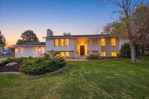 Split level with brick siding, a front lawn, a garage, and a chimney
