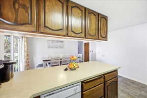 Kitchen featuring light countertops, white dishwasher, and wood finish cabinetry