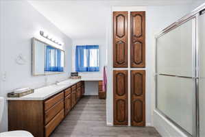 Full upstairs bathroom with vanity, combined bath / shower with glass door, and dark wood-type flooring