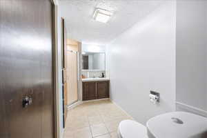 Basement bathroom with a stall shower, vanity, and light tile floors