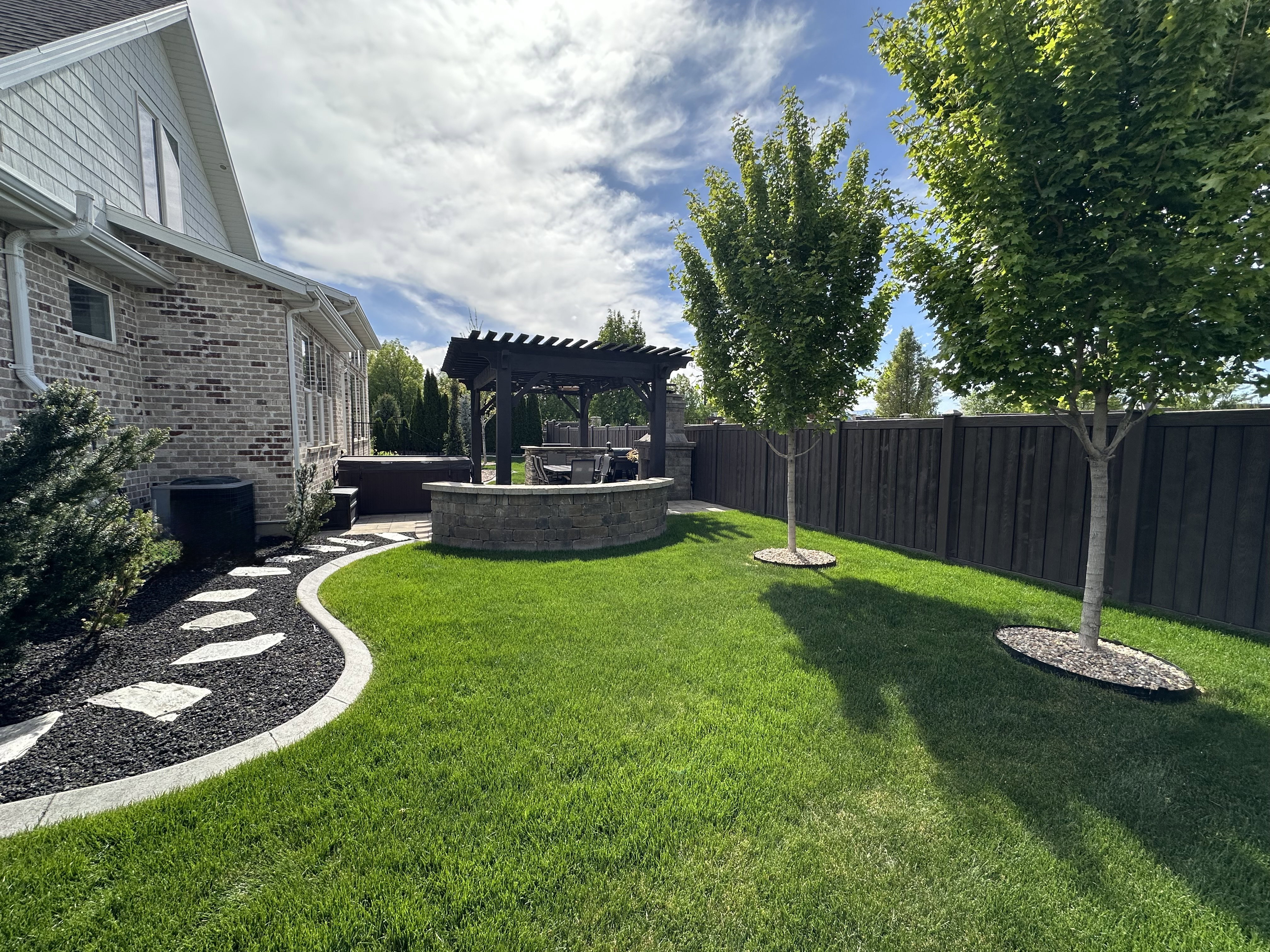 Fenced backyard featuring a pergola, a patio area, and a jacuzzi