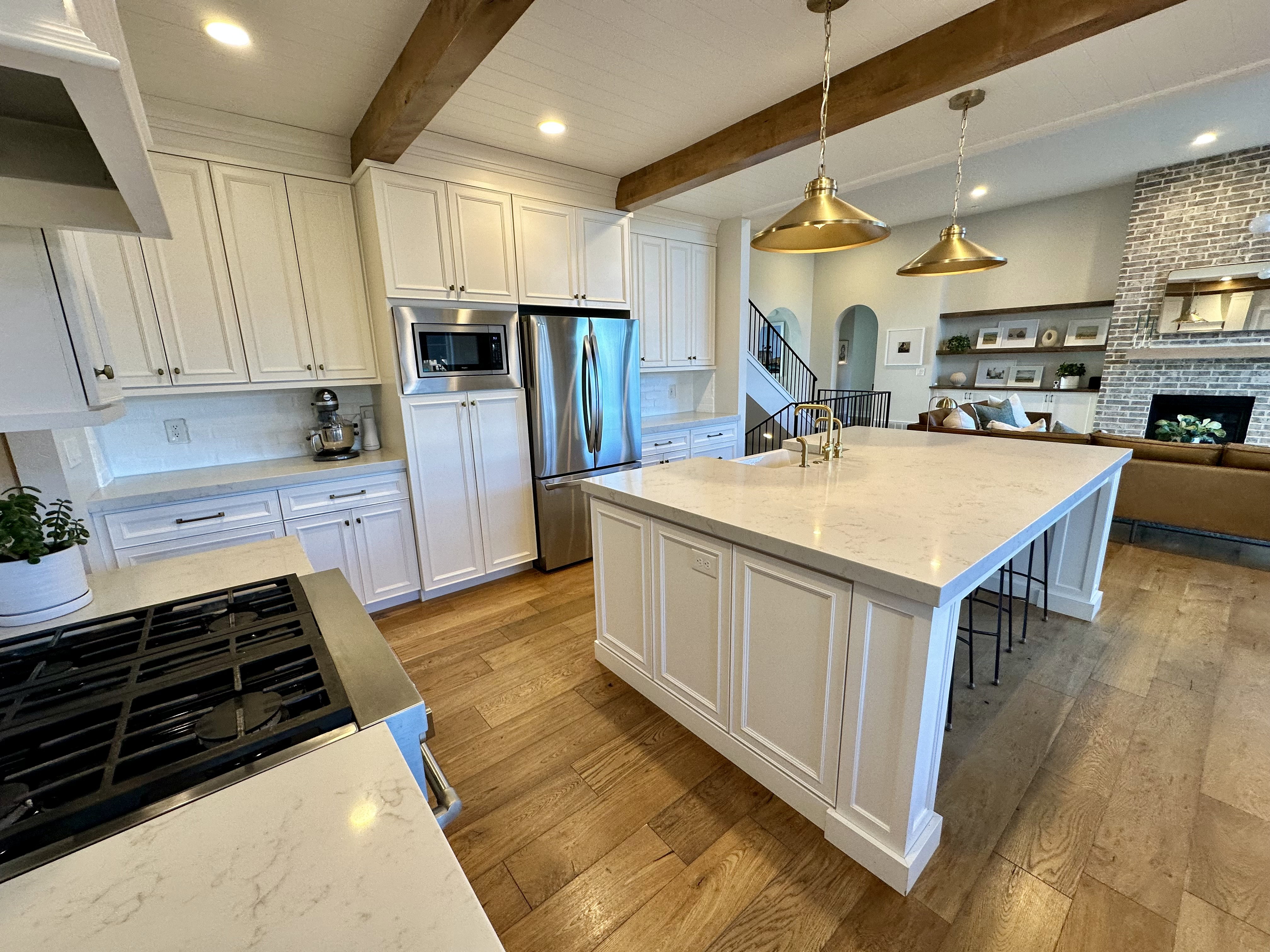 Kitchen with white cabinets, light stone counters, open floor plan, light wood-style flooring, and stainless steel appliances