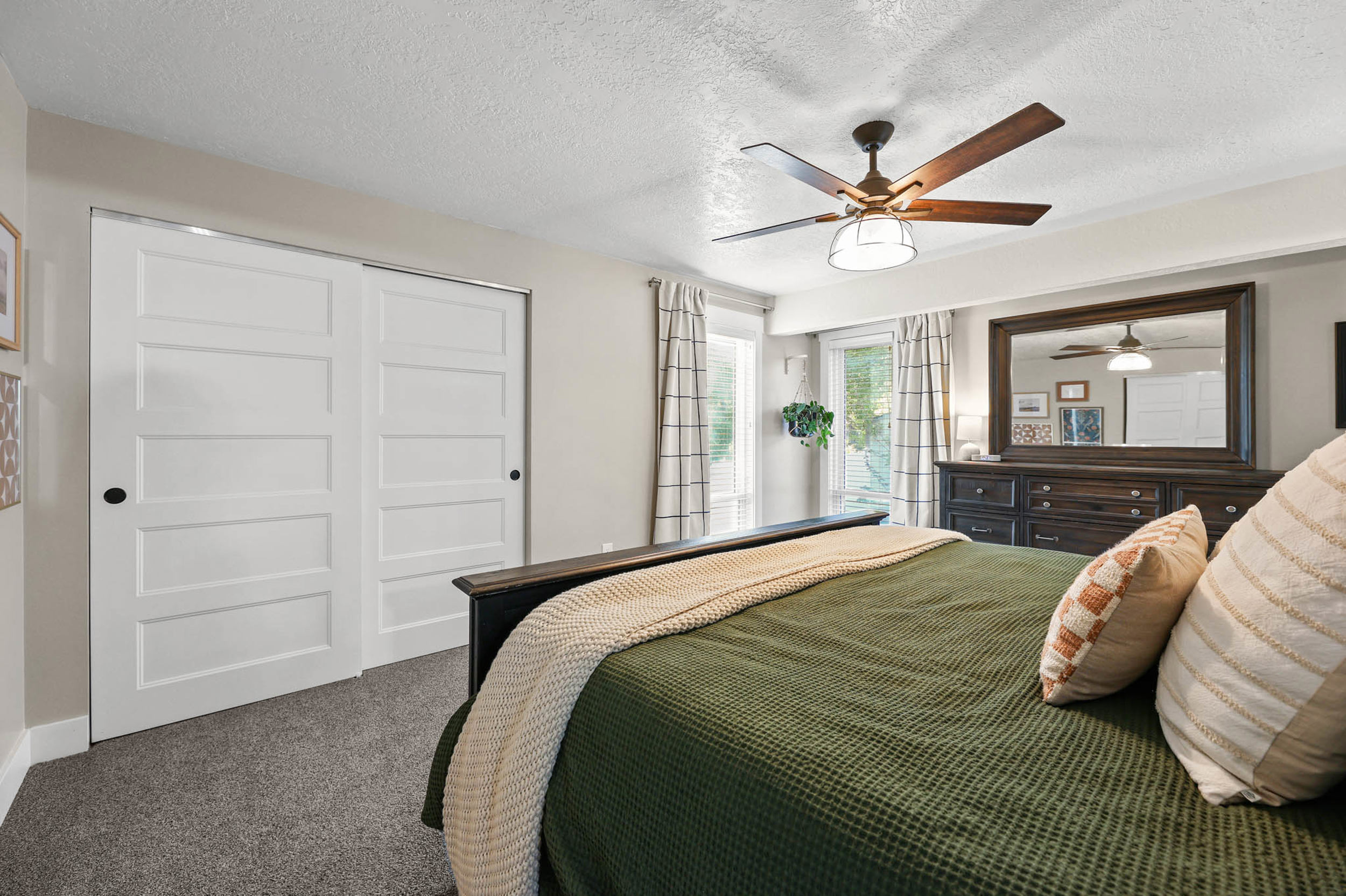 Bedroom with a textured ceiling, a closet, dark colored carpet, and a ceiling fan