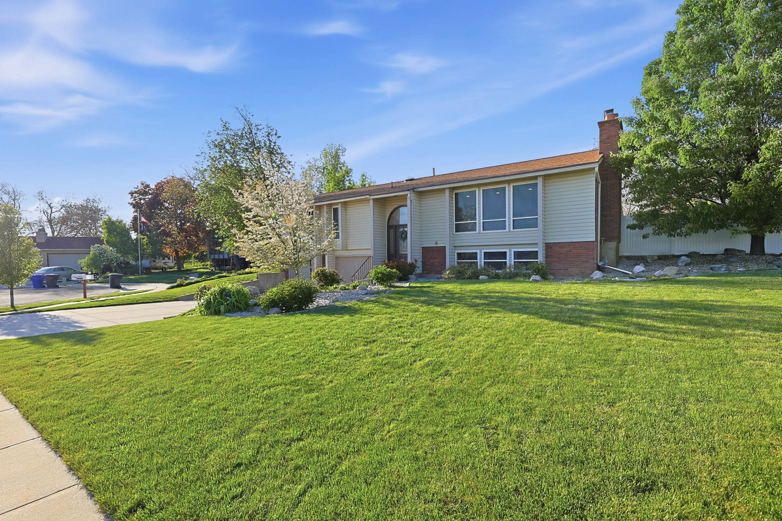 Split foyer home featuring a front lawn, a chimney, brick siding, and concrete driveway