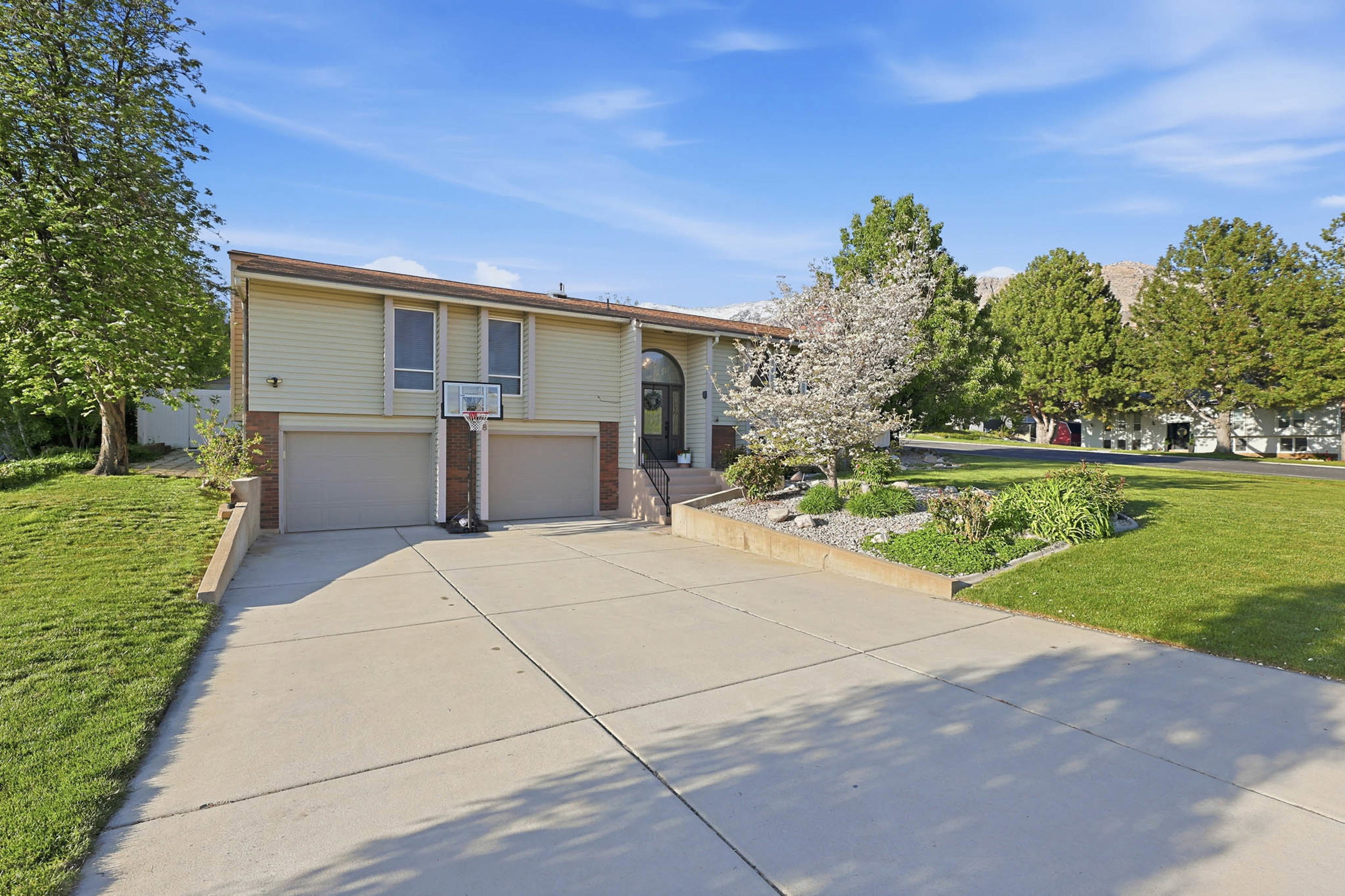 Raised ranch featuring a front yard, an attached garage, brick siding, and concrete driveway