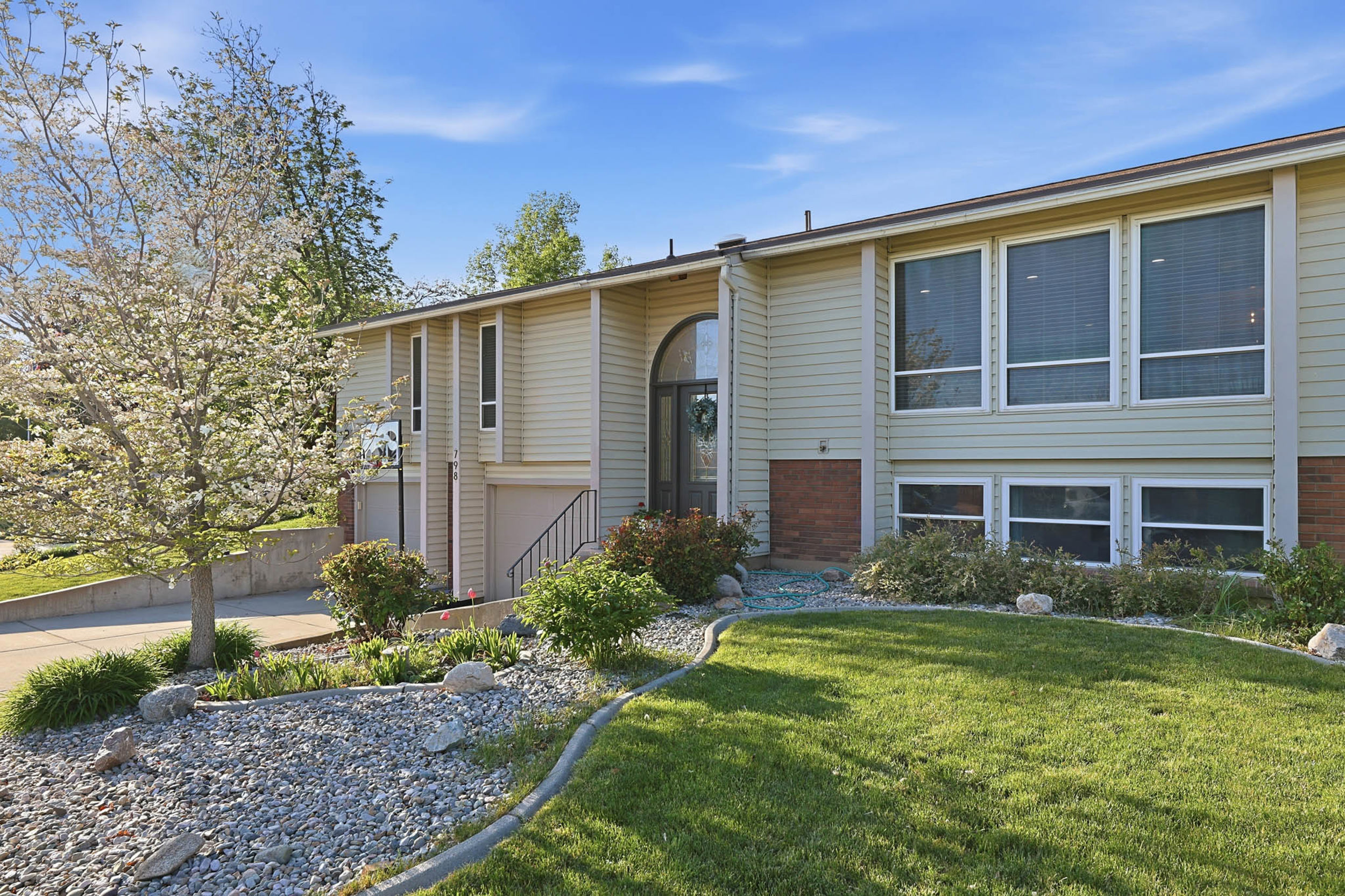 Raised ranch with a front lawn, an attached garage, and driveway