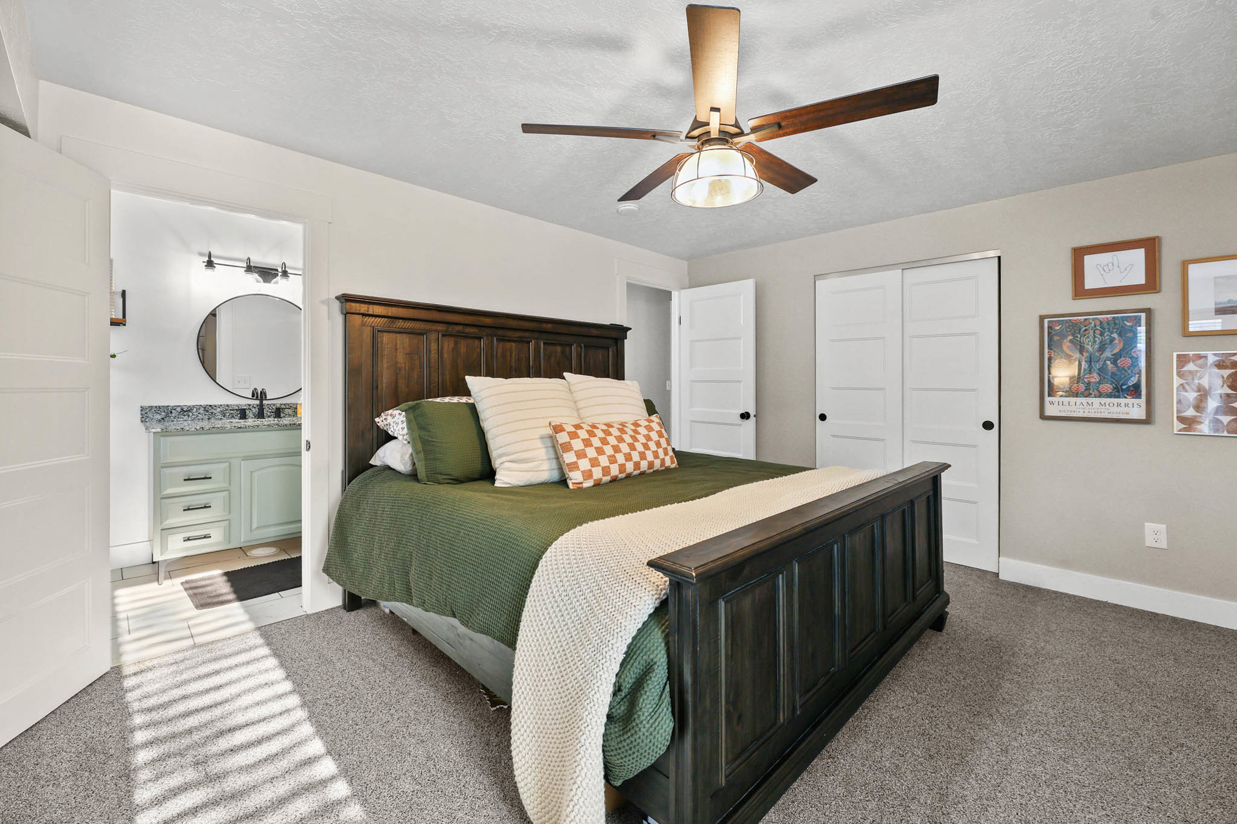 Bedroom featuring a textured ceiling, carpet floors, a closet, ceiling fan, and ensuite bath