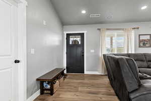 Foyer entrance with vaulted ceiling, light wood finished floors, and recessed lighting
