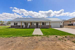 View of front of home featuring board and batten siding, covered porch, driveway, an attached garage, and a front yard